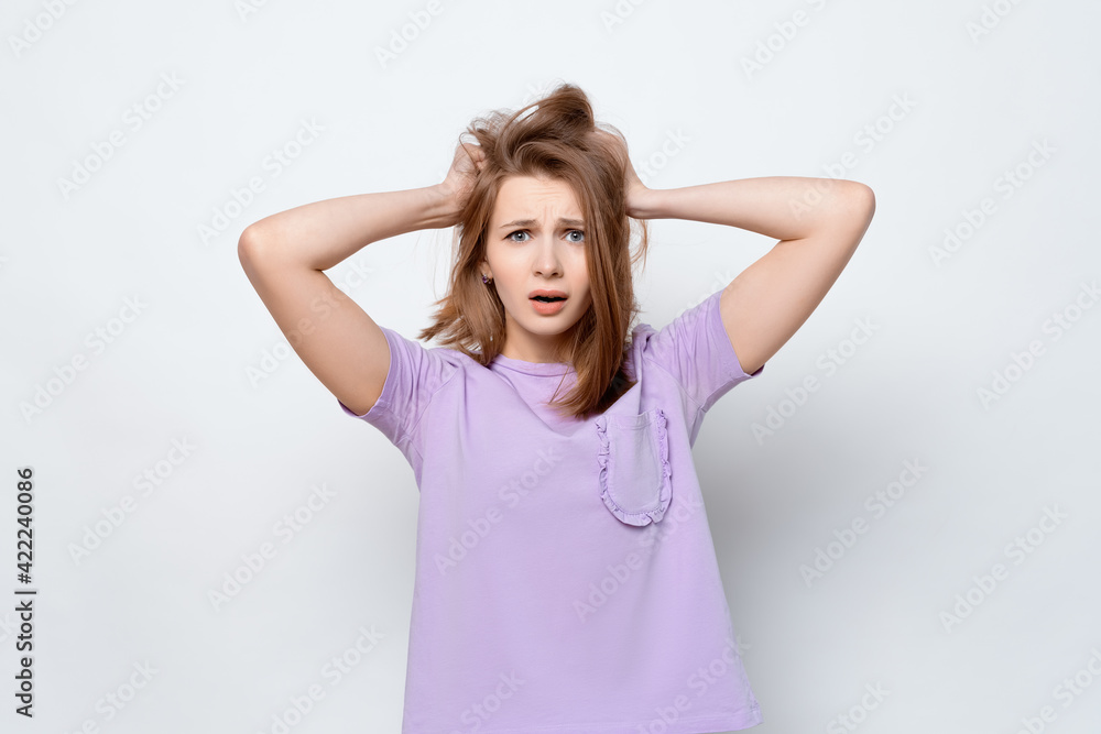 Portrait of girl in casual t shirt in panic grabbing her head in fear or frustration. Stress and mental health Portrait of girl in casual t shirt in panic grabbing her head in fear or frustration. Stress and mental health