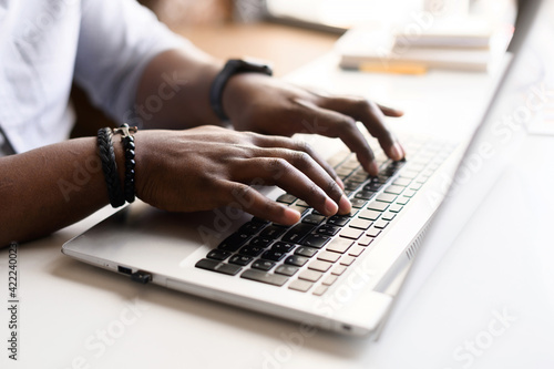 Close up image of male hands with accessories typing text on the laptop keyboard, working, responding to client e-mail, buying ordering items online. Electronics and modern wireless technology concept