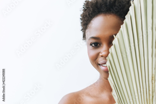 Beautiful smiling afro american young woman beauty fashion model looking at camera with dry leaf on white background, eco concept, nature beauty photo