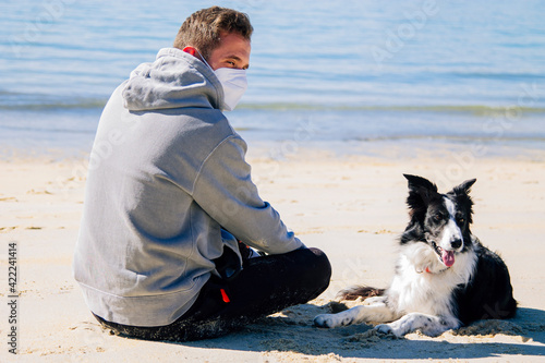 young man in medical mask with his dog on the beach © tetxu