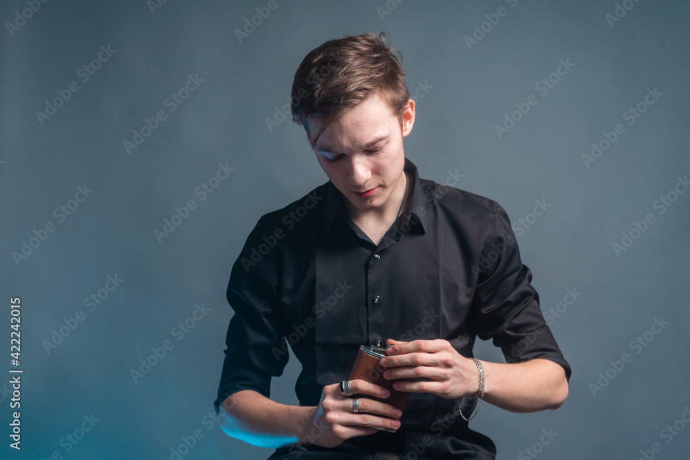 The guy sits on the bar stool and holds a flask with alcohol in his hands The guy sits on the bar stool and holds a flask with alcohol in his hands