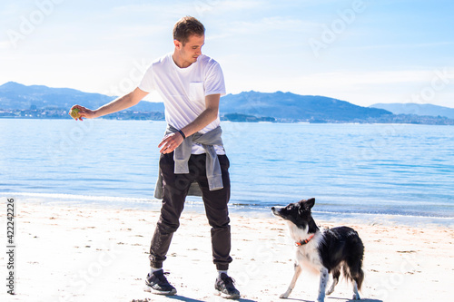 young man playing with his dog on the beach