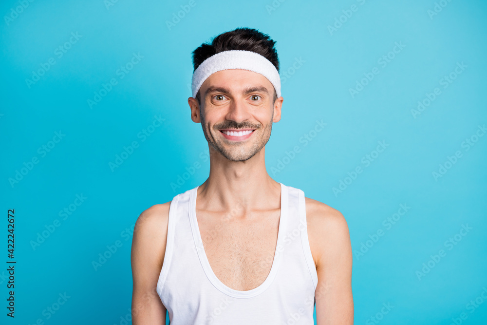Portrait of positive sportive man look in camera wear white sport undershirt isolated over blue color background Portrait of positive sportive man look in camera wear white sport undershirt isolated over blue color background