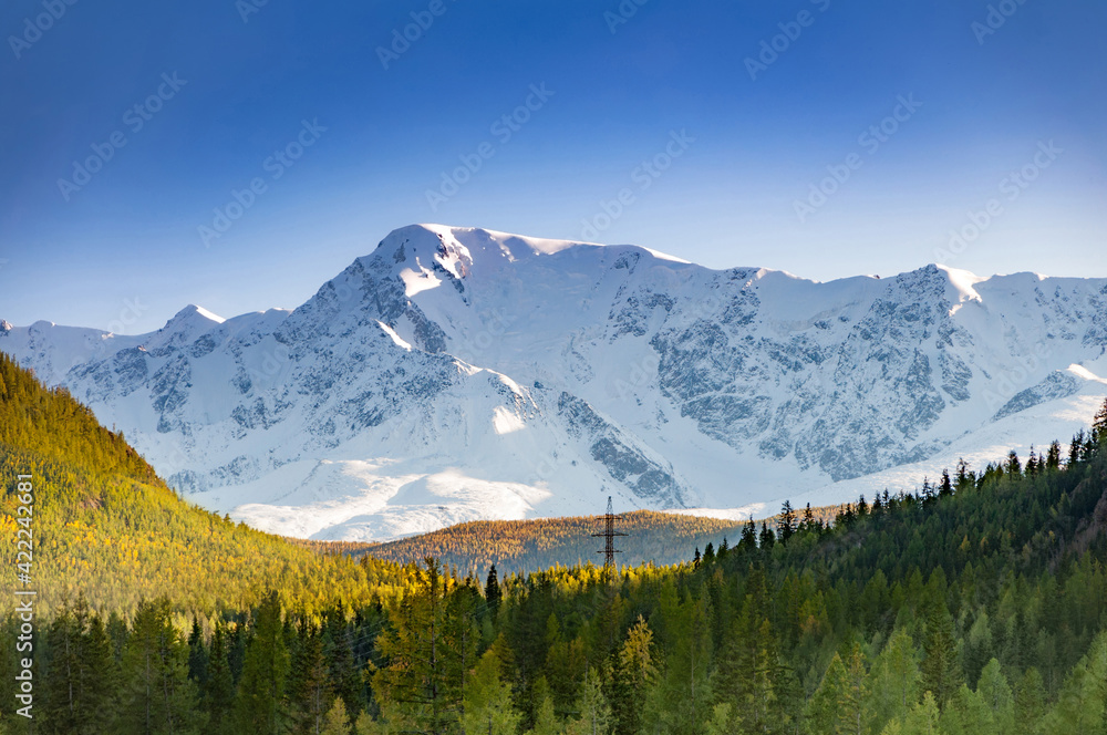 Scenic aerial view over snow capped mountain range, surrounded by siberian forest. Altai autumn landscape, Russia
