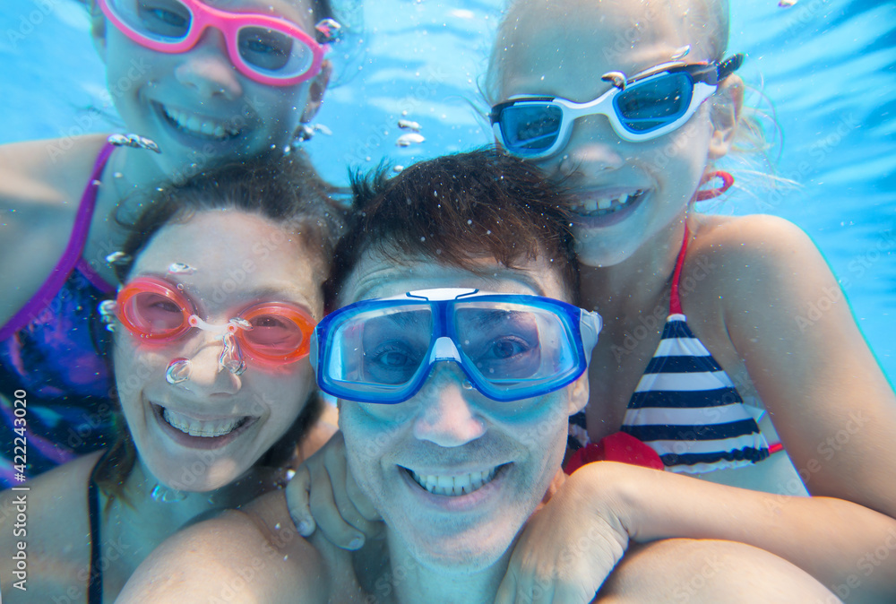 Naklejka premium underwater photo of little boy with his family swimming in pool