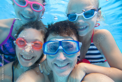 underwater photo of  little boy with his family  swimming  in pool © yanlev