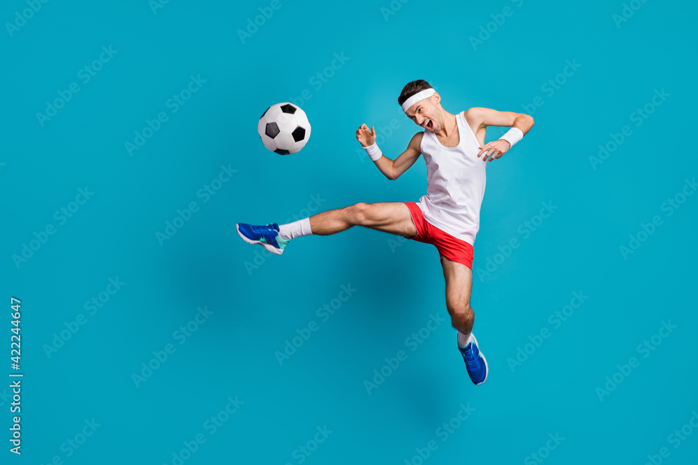 Full length photo of crazy football player kick ball in jump wear white tank-top isolated over blue color background