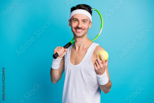 Photo of young sportsman happy positive smile hold tennis racquet ball isolated over blue color background © deagreez