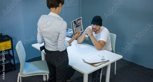 Fotografie Woman detective shows pictures of suspected criminals and robber