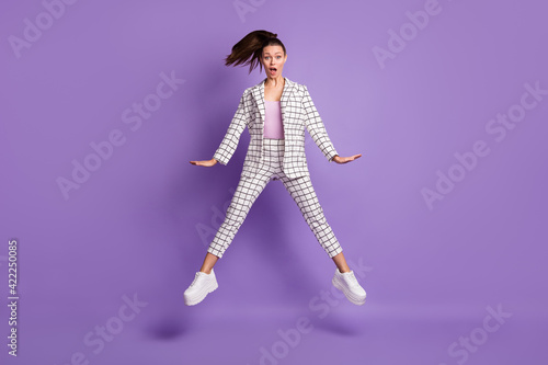 Full size photo of young attractive girl amazed shocked surprised news fake novelty jump up isolated over purple color background