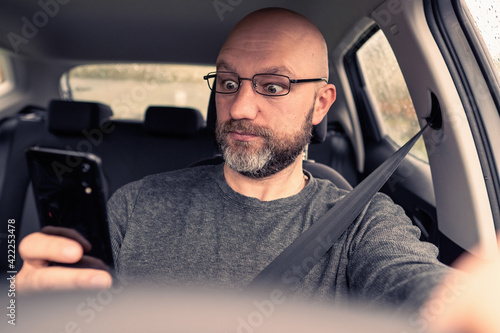 Bilde på lerret Male car driver in a car holding smart phone in his hand