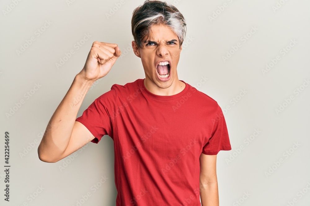 Young hispanic man wearing casual clothes angry and mad raising fist frustrated and furious while shouting with anger. rage and aggressive concept. Young hispanic man wearing casual clothes angry and mad raising fist frustrated and furious while shouting with anger. rage and aggressive concept.