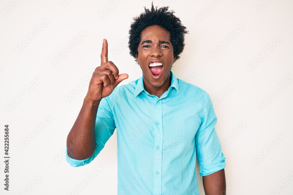 Handsome african american man with afro hair wearing casual clothes pointing finger up with successful idea. exited and happy. number one. Handsome african american man with afro hair wearing casual clothes pointing finger up with successful idea. exited and happy. number one.