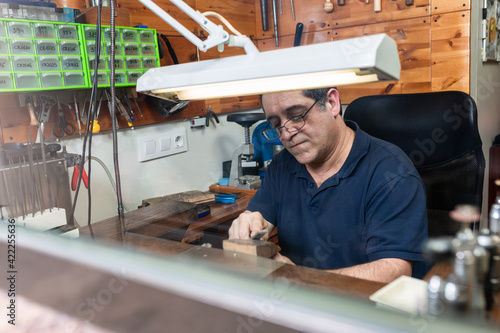 goldsmith sands a silver ring on the workbench.