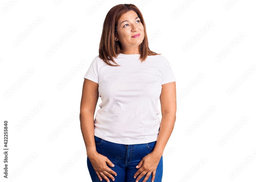 Middle age latin woman wearing casual white tshirt smiling looking to the side and staring away thinking. Middle age latin woman wearing casual white tshirt smiling looking to the side and staring away thinking.