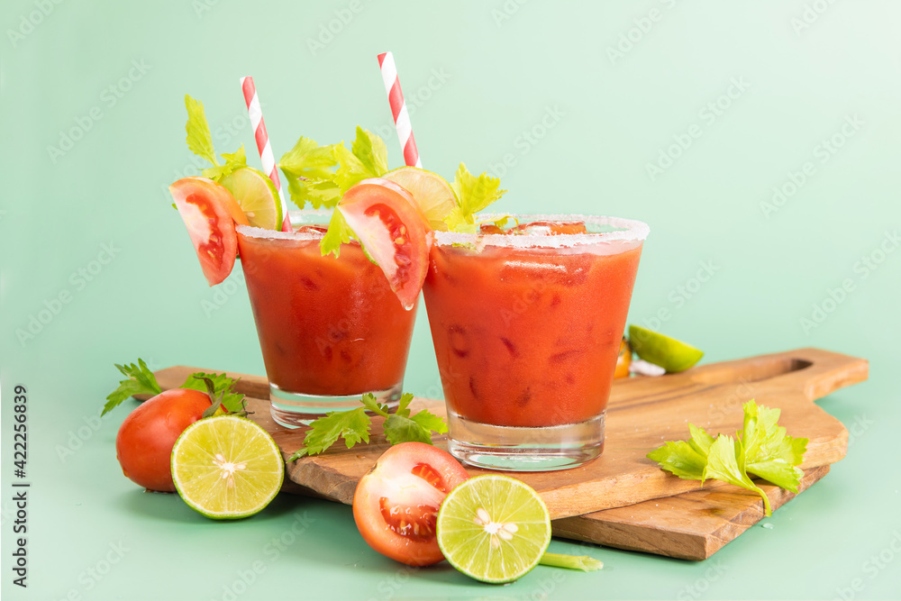 glass glass of tomato juice, lime with fresh bright bunch of tomatoes isolated on green background, green parsley. vegetable drink. glass glass of tomato juice, lime with fresh bright bunch of tomatoes isolated on green background, green parsley. vegetable drink.
