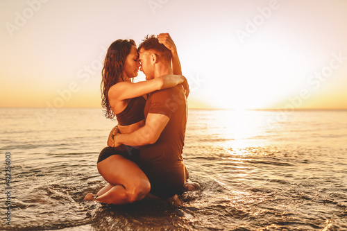 Photography Happy young fit couple in sea or ocean hug each other with love at summer sunset