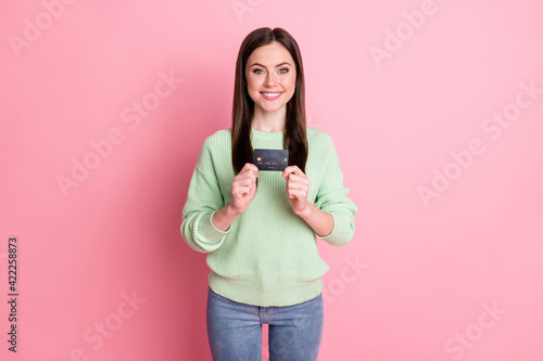 Photo of optimistic sweet brunette girl show card wear lime shirt jeans isolated on pink color background