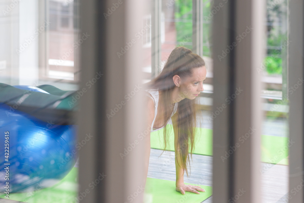 Caucasian woman exercising with exercise ball. Fitness girls flexing abdominal muscles with fit ball in gym room Caucasian woman exercising with exercise ball. Fitness girls flexing abdominal muscles with fit ball in gym room