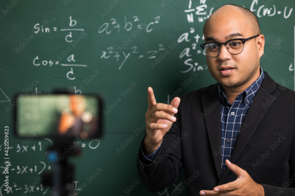 Indian young teacher man teaching online video conference live stream by smartphone. Asian teacher teaching mathematics class webinar online for students learning.