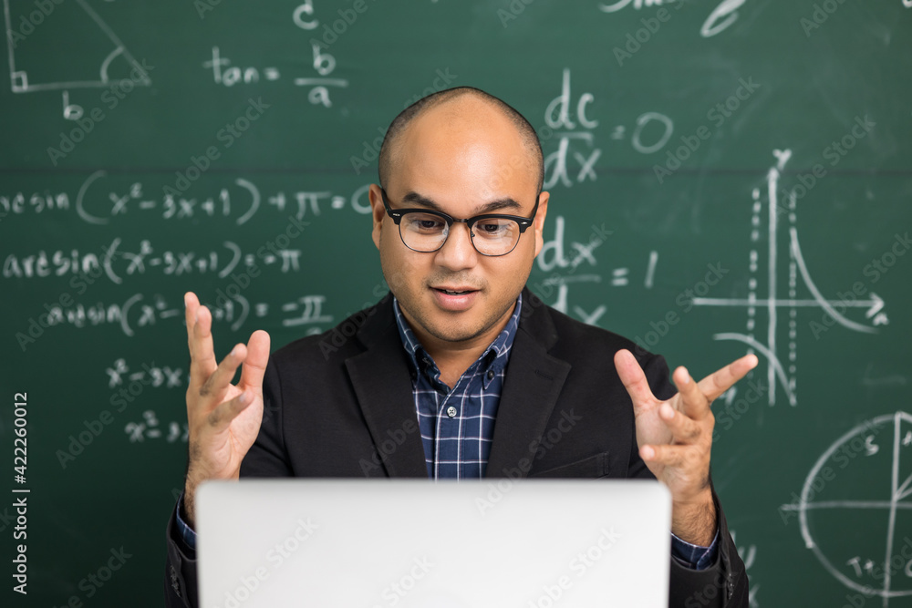 Indian young teacher man sitting teaching online video conference live stream by laptop. Asian teacher teaching mathematics class webinar online for students learning. Indian young teacher man sitting teaching online video conference live stream by laptop. Asian teacher teaching mathematics class webinar online for students learning.
