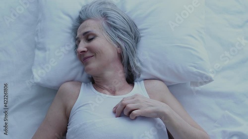 Wallpaper Mural Attractive mature woman sleeping and smiling seeing pleasant dreams, top view Torontodigital.ca