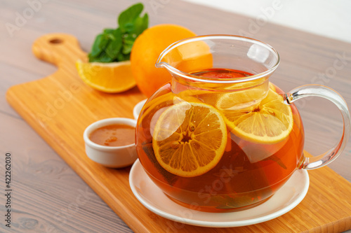 Glass teapot with black tea and pieces of citrus