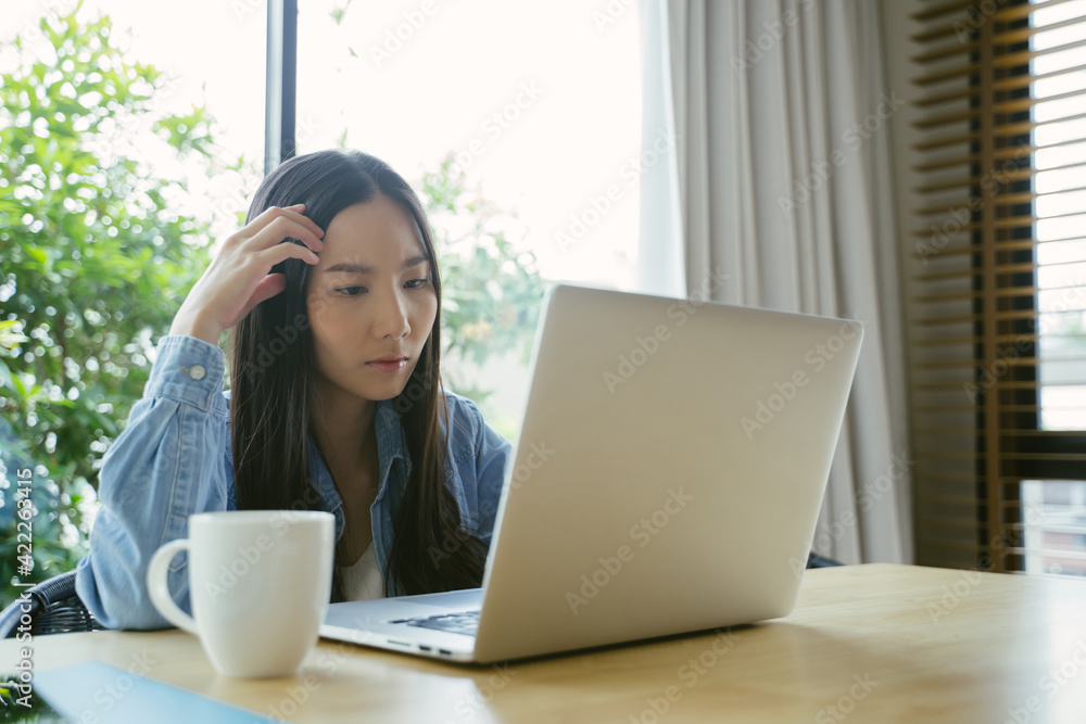 Serious Asian woman using a laptop working at home. Serious Asian woman using a laptop working at home.