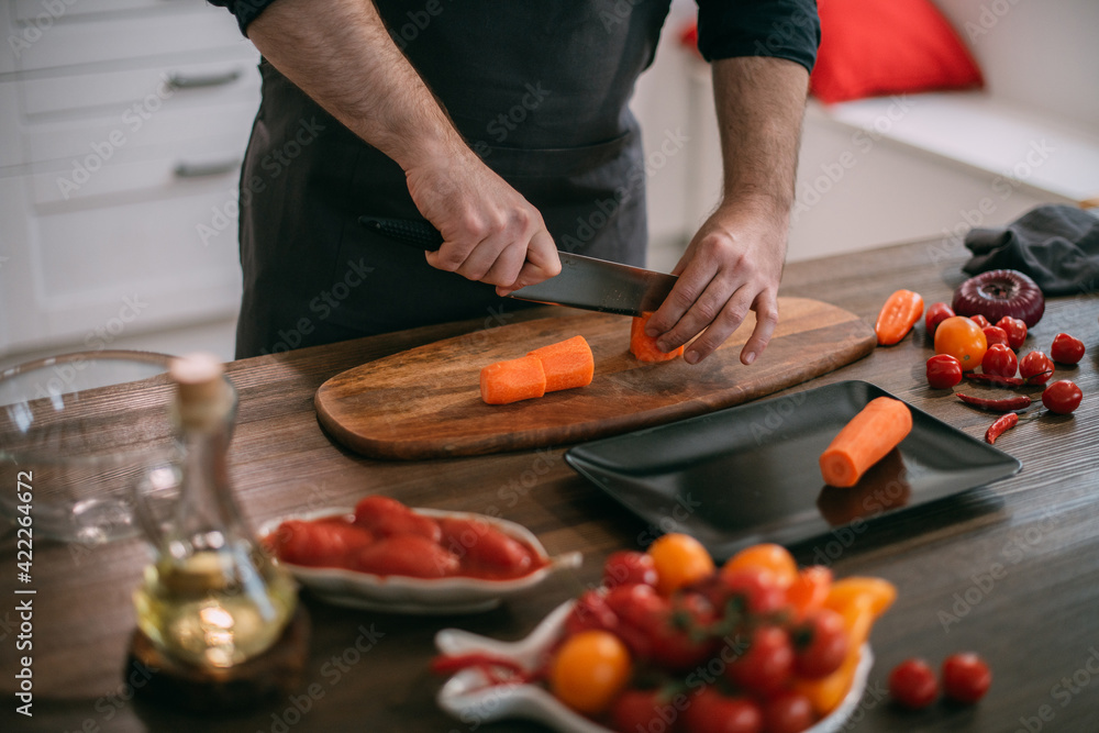 A male cook prepares vegetables at home in the kitchen