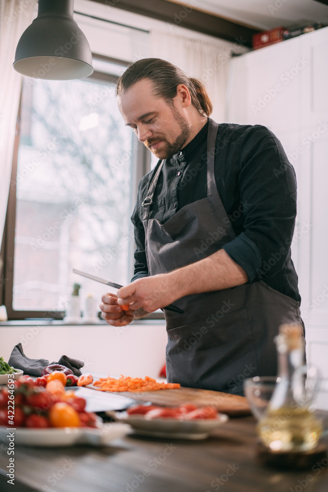 A male cook prepares vegetables at home in the kitchen A male cook prepares vegetables at home in the kitchen