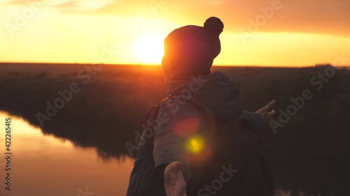 Man traveler whirls at sunset and laughs, adventurer in free flight of fantasy, vacation on a camping trip, meeting the sunrise on a high mountain, bright glare of the sun in nature in the park