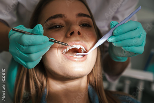 Woman sitting in medical chair while dentist fixing her teeth