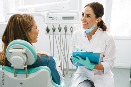 European mid dentist woman smiling while working with patient photo