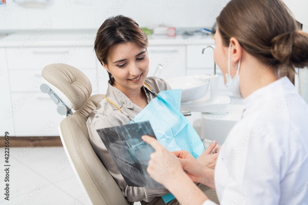 Fototapeta premium A female dentist discussing an x-ray with her patient at the cli