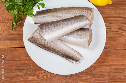 Top view of raw hake on dish on rustic table