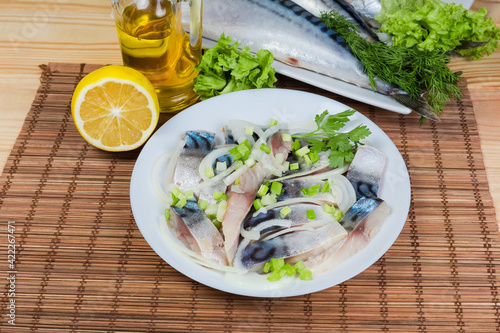 Sliced salted Atlantic mackerel with onion against of whole fish