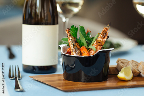 Schilderij op canvas Spanish national gambas pil pil shrimps in a black bowl with a bottle of wine
