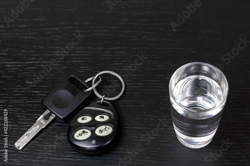 On the black table are the car keys and a shot of vodka close-up with copy space. Concept of drunk driving