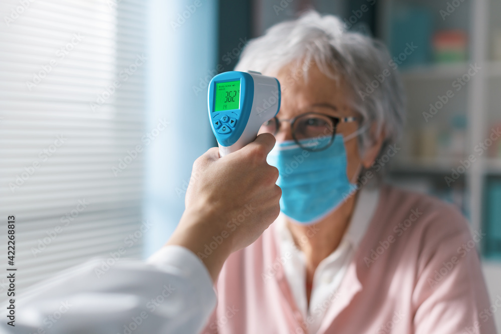 Doctor checking a senior patient's body temperature Doctor checking a senior patient's body temperature