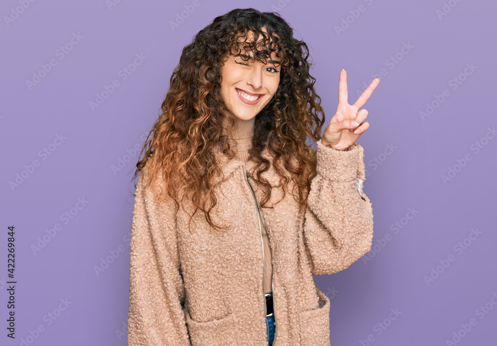 Young hispanic girl wearing winter clothes smiling with happy face winking at the camera doing victory sign. number two. Young hispanic girl wearing winter clothes smiling with happy face winking at the camera doing victory sign. number two.