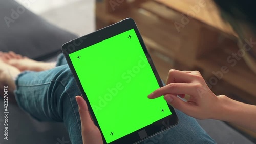 Close up of woman holding in hands a digital tablet with green screen for internet online, chroma key screen for advertising.