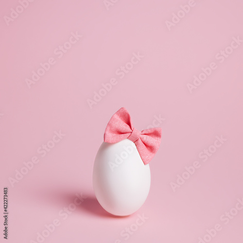 Cute Easter egg with bow tie headband on pastel pink background. Minimal Easter or food concept.