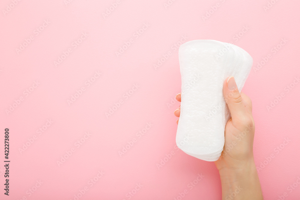 Young adult woman hand holding new white panty liners on light pink table background. Pastel color. Closeup. Female daily hygiene. Empty place for text. Top down view. Copy space. Young adult woman hand holding new white panty liners on light pink table background. Pastel color. Closeup. Female daily hygiene. Empty place for text. Top down view. Copy space.