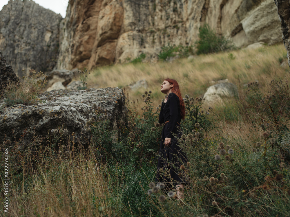 Fototapeta premium A woman in a black dress are walking in the mountains on nature in autumn