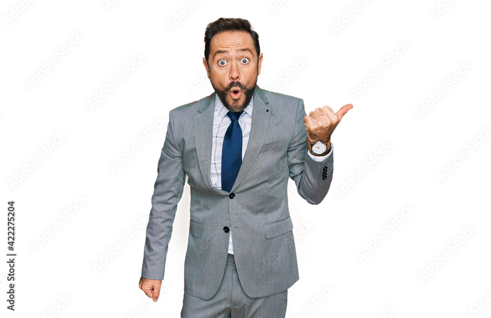 Middle age man wearing business clothes surprised pointing with hand finger to the side, open mouth amazed expression. Middle age man wearing business clothes surprised pointing with hand finger to the side, open mouth amazed expression.