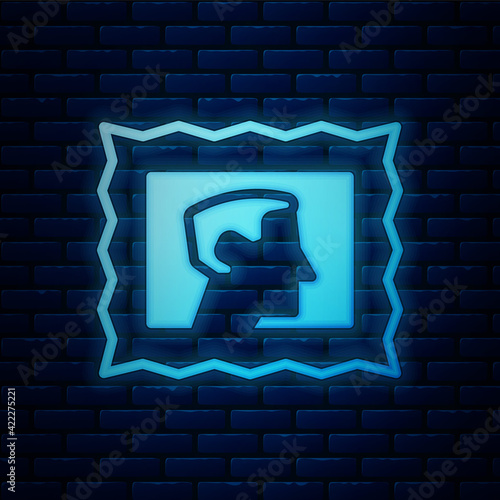 Glowing neon Postal stamp icon isolated on brick wall background. Vector