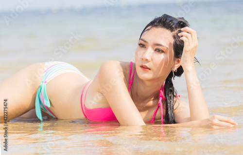 Beautiful Asian woman lounging on the beach happily. beautiful girl enjoying relaxing on beautiful summer beach