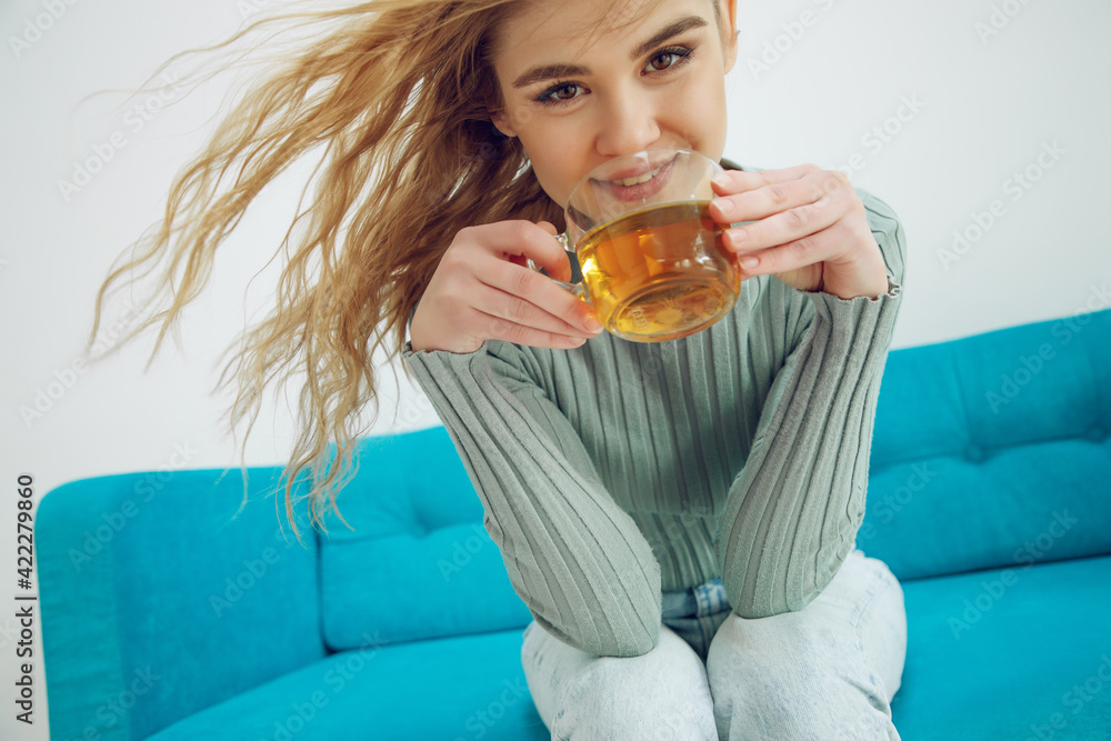 Young woman sitting at home and drinking tea, interior. High quality photo. Young woman sitting at home and drinking tea, interior. High quality photo.