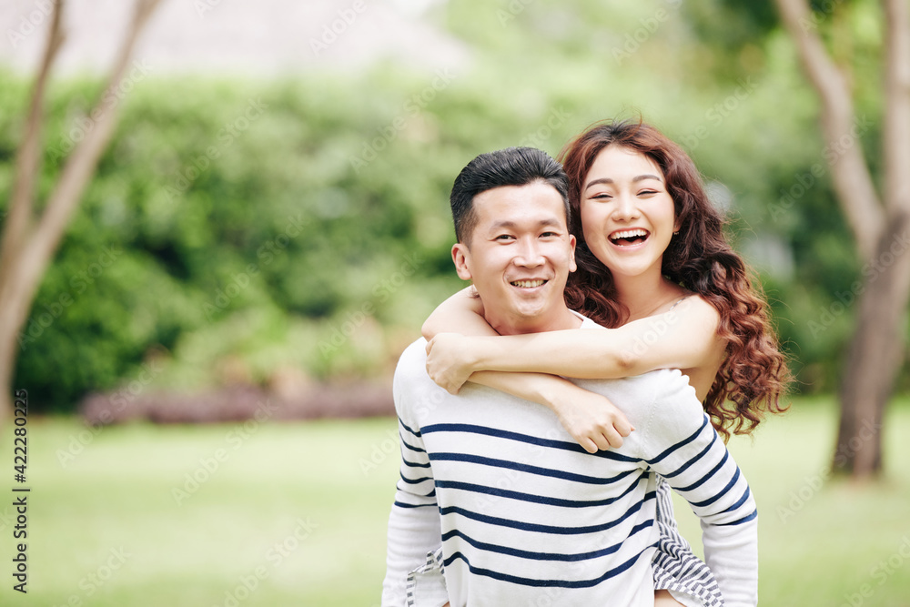 Portrait of happy excited young Vietnamese couple hugging and looking at camera