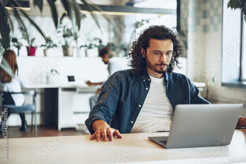 Young businessman, successful freelancer working online on computer, sitting in modern office